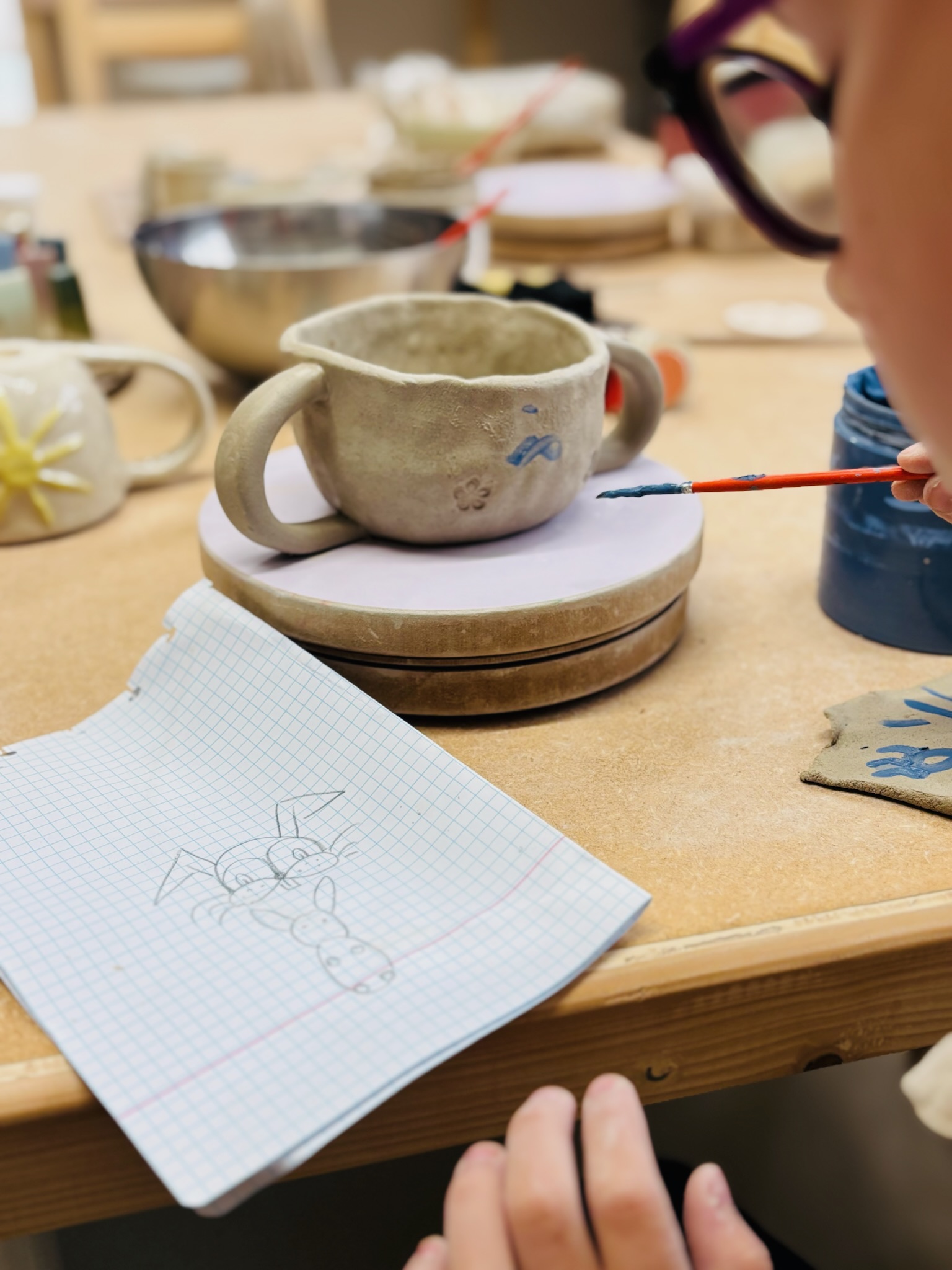 Enfant peint un pot en argile.
